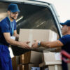 Young couriers cooperating while unloading packages from deliver